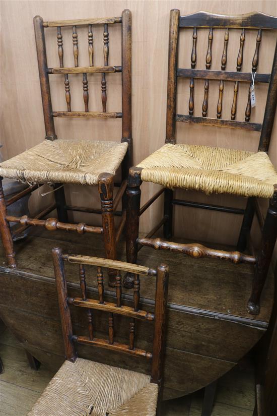 Three early 19th century two-tier spindle back chairs with rush seats. An oak drop-leaf table fitted single drawer, W.140cm (with leave
